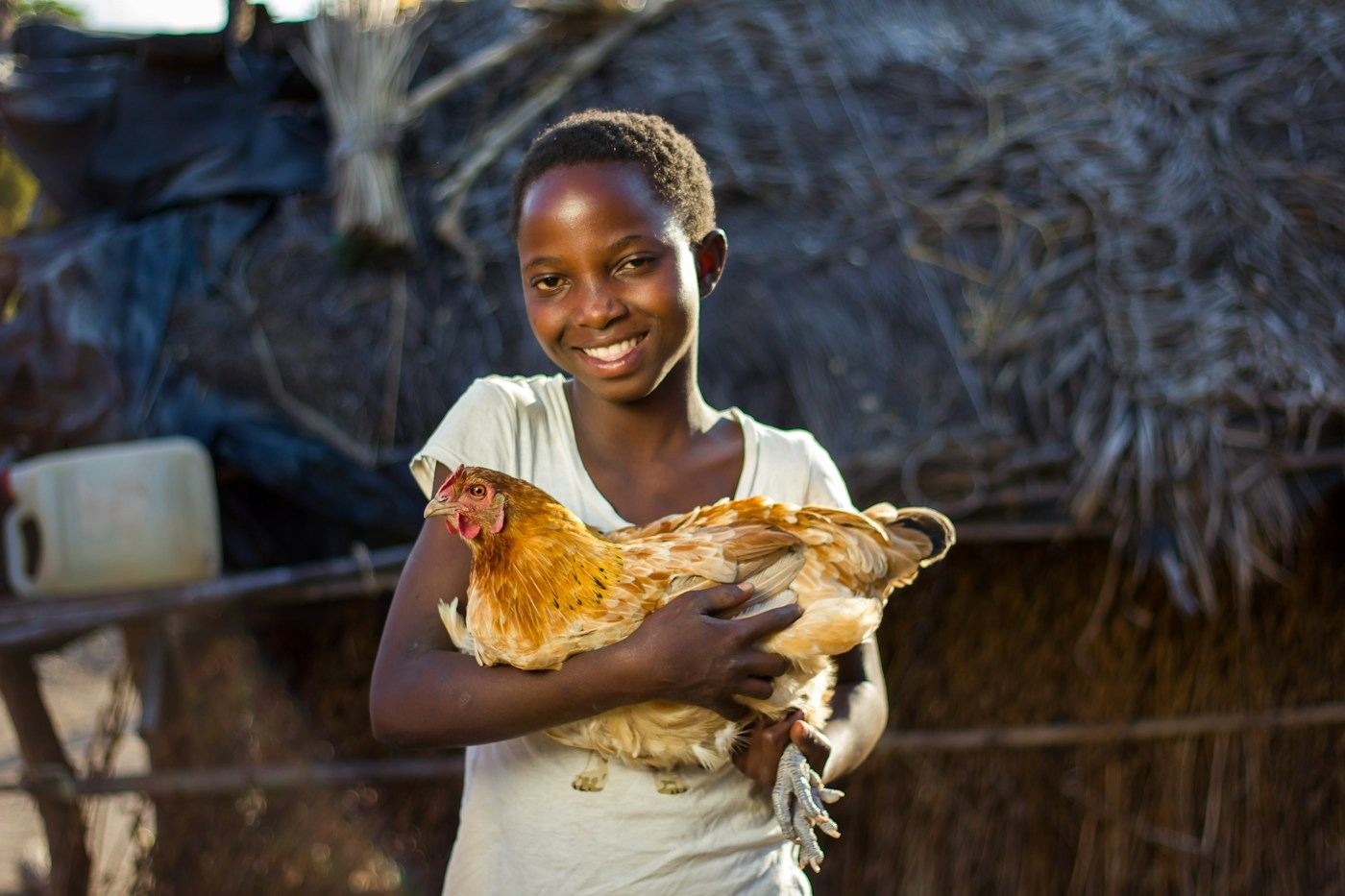 Jeune fille souriante tenant une poule dans ses bras